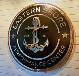 Large round Eastern Shore Performance Center custom metal sign installed on a gym wall