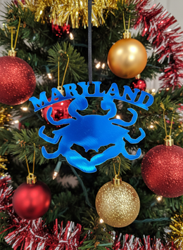 Blue crab-shaped ornament with 'Maryland' text on a Christmas tree with red and gold ornaments.