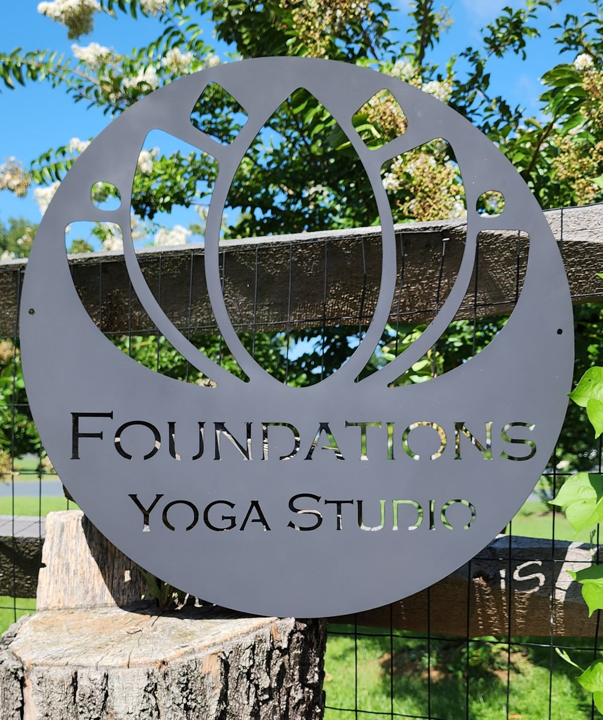 Round gray powder coated metal logo sign for Foundations Yoga Studio