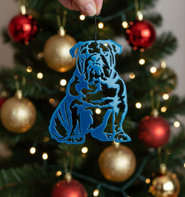Blue bulldog ornament hanging on a decorated Christmas tree with red and gold baubles.