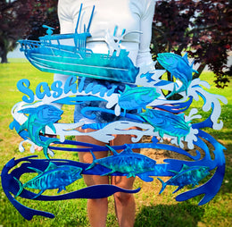 Customer holding colorful boat and fish artwork by Elite Metalworking