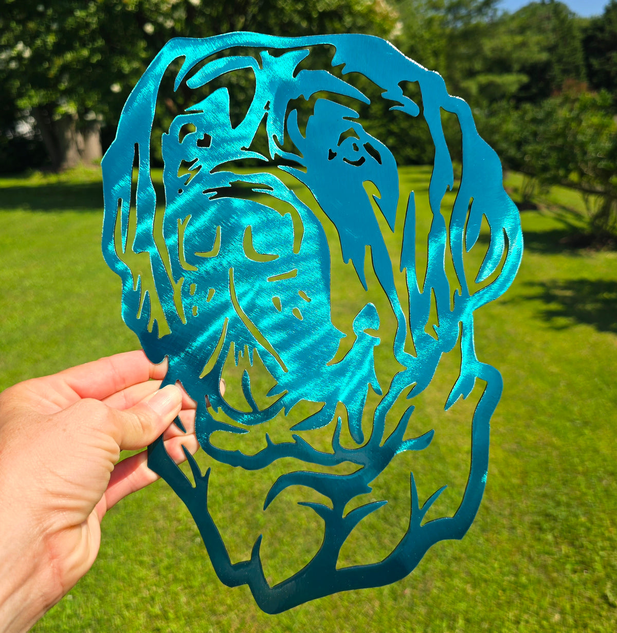 Blue and green dog-face metal artwork held outdoors by Elite Metalworking