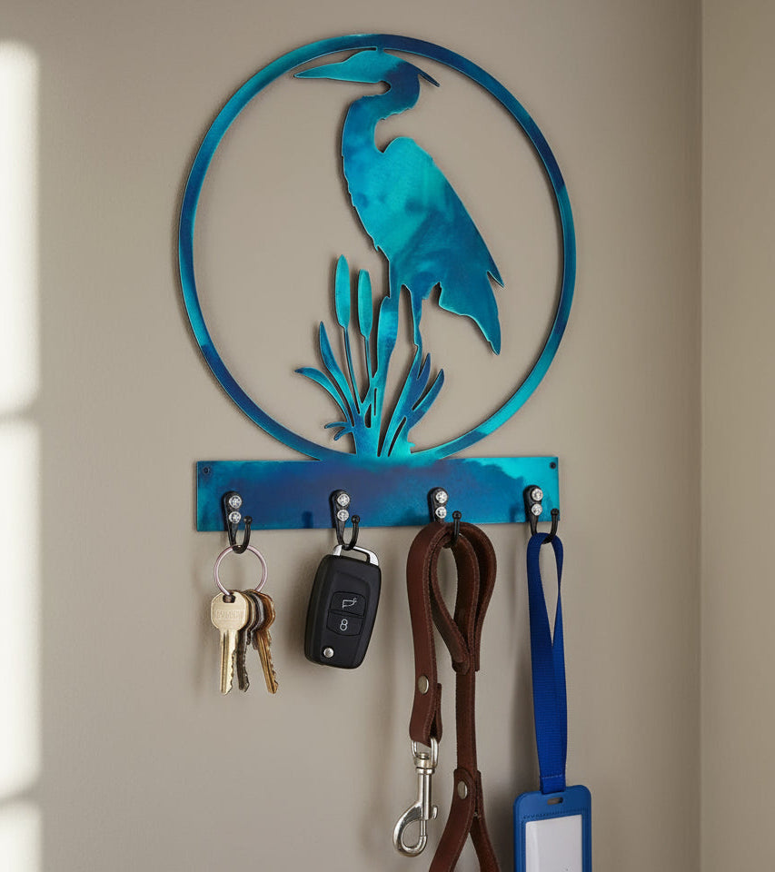 Decorative wall hook with heron design holding keys, a car key, a leash, and a tag on a beige wall.