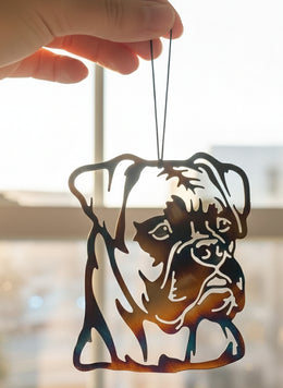 A custom metal art ornament in the shape of a boxer dog with a multicolored, reflective finish.