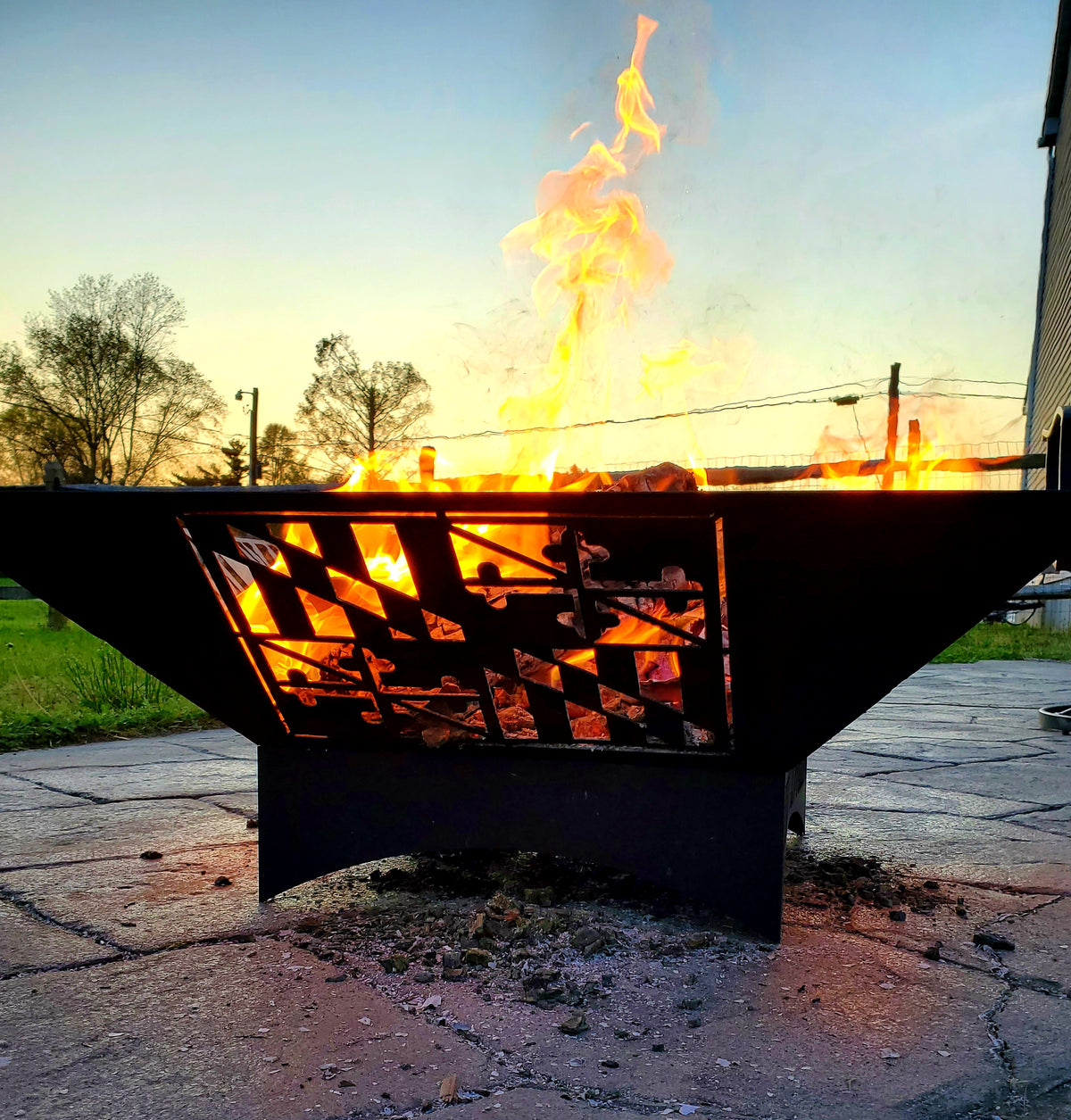 The Elite Fire Pit burning outdoors with a cut-steel Maryland flag side design