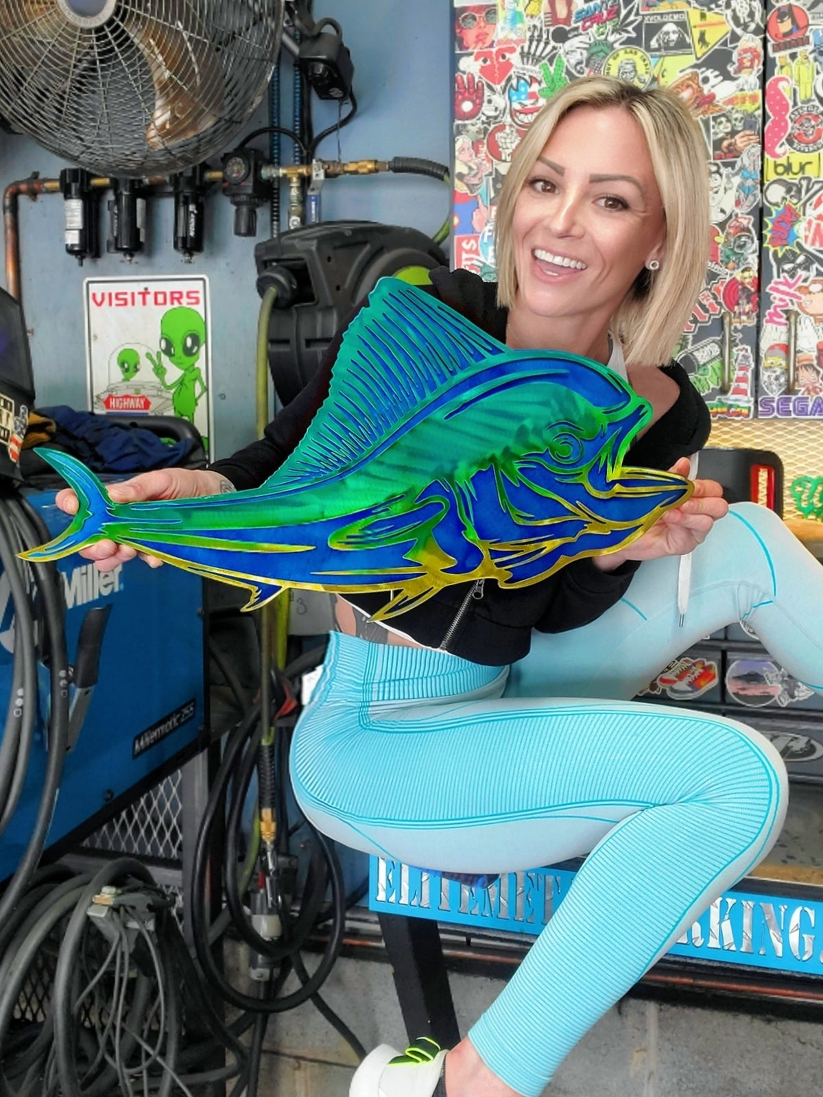 Customer holding blue and green fish metal art by Elite Metalworking