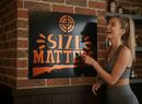Woman pointing at a sign with 'SIZE MATTERS' text in an indoor setting.